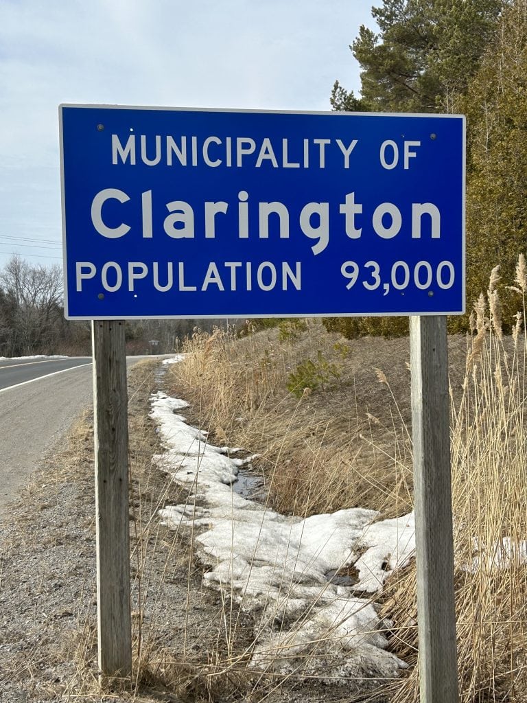 Clarington Sign, displaying vibrant lettering on a classic background, set along a busy roadway, marking the gateway to Clarington, Ontario.