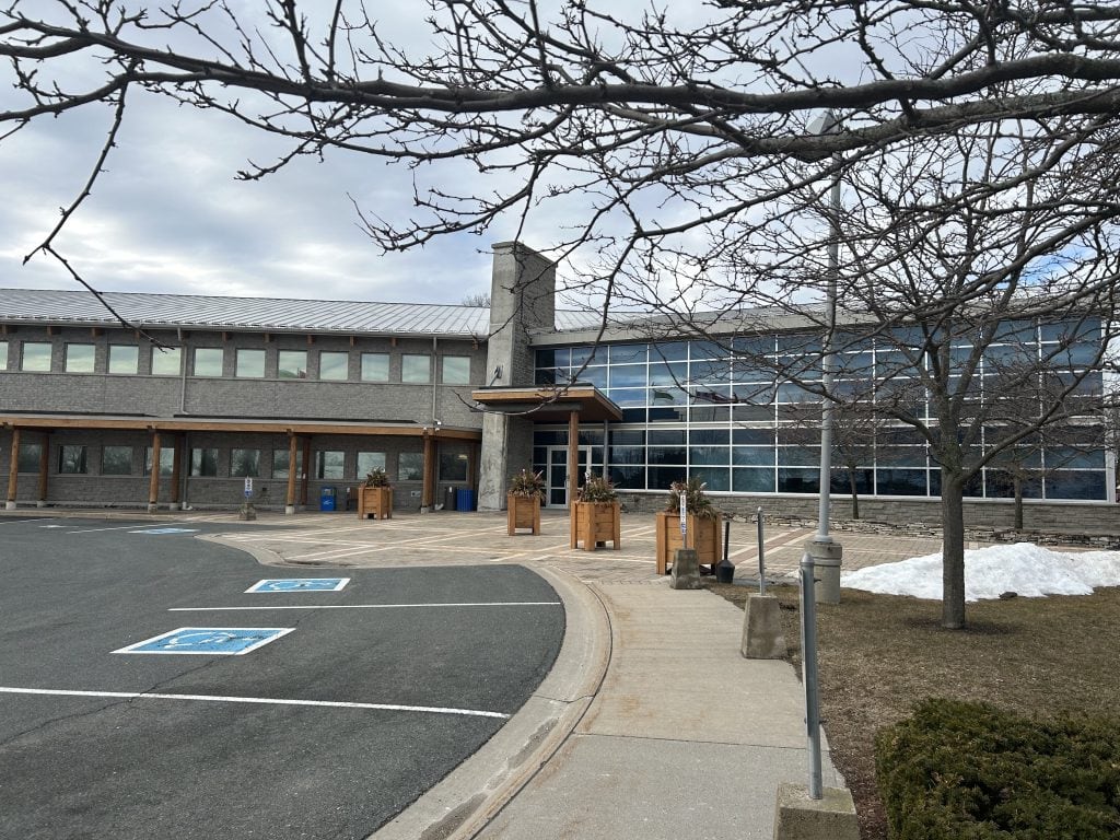 Northumberland County Real Estate: Northumberland Office showcases a modern design with its glass and metal facade, creating a reflective surface that mirrors the surrounding natural elements, positioned in a contemporary business environment in Ontario.