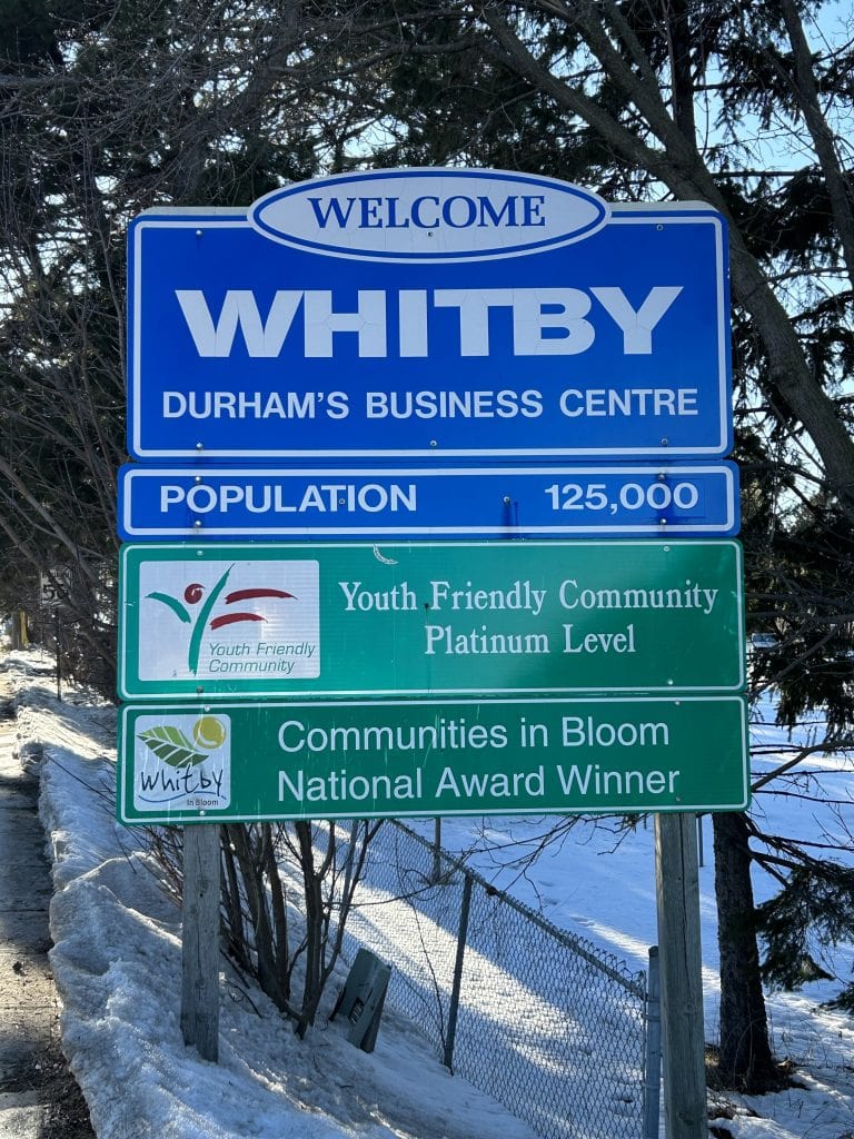 Whitby Sign, showcasing a classic design with elegant lettering against a natural stone backdrop, surrounded by vibrant landscaping, marking the gateway to Whitby, Ontario.