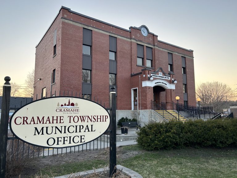 Cramahe Municipal Building exhibits classic architecture with a white wooden facade and green shutters, surrounded by a well-maintained lawn and mature trees, reflecting the quaint charm of this Ontario township